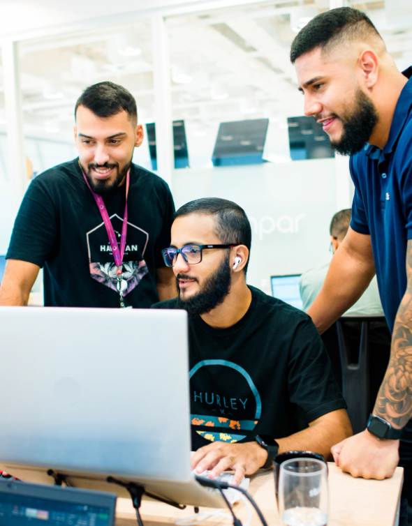 Colaboradores ímpar ao redor do notebook olhando para a tela.